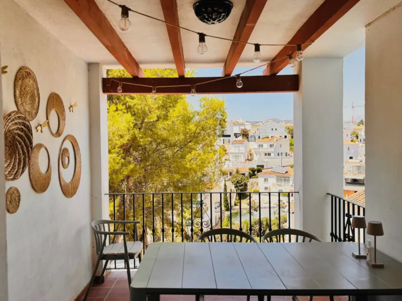 Covered terrace with a dining table and a view of the trees