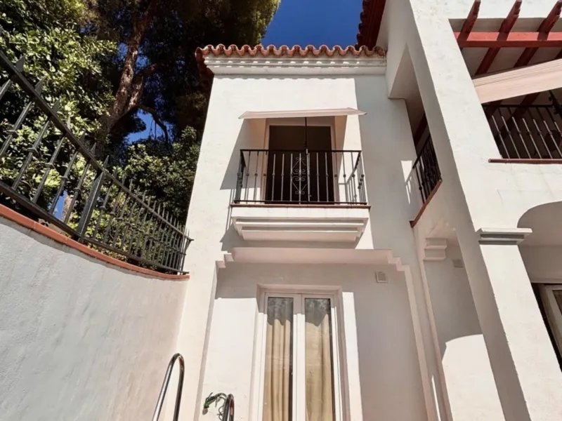 Whitewashed Andalusian house with balconies, seen from the pool