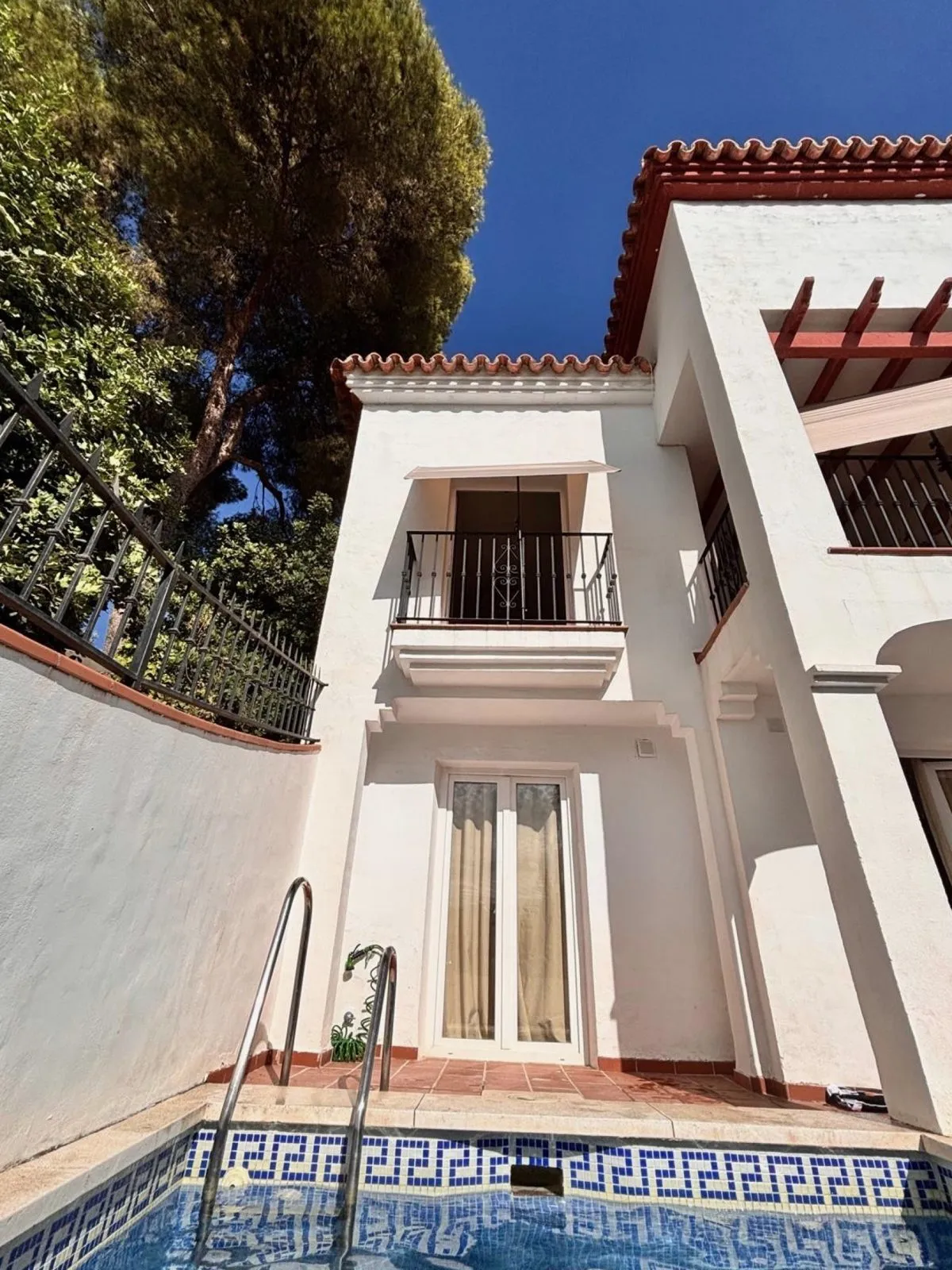 Whitewashed Andalusian house with balconies, seen from the pool