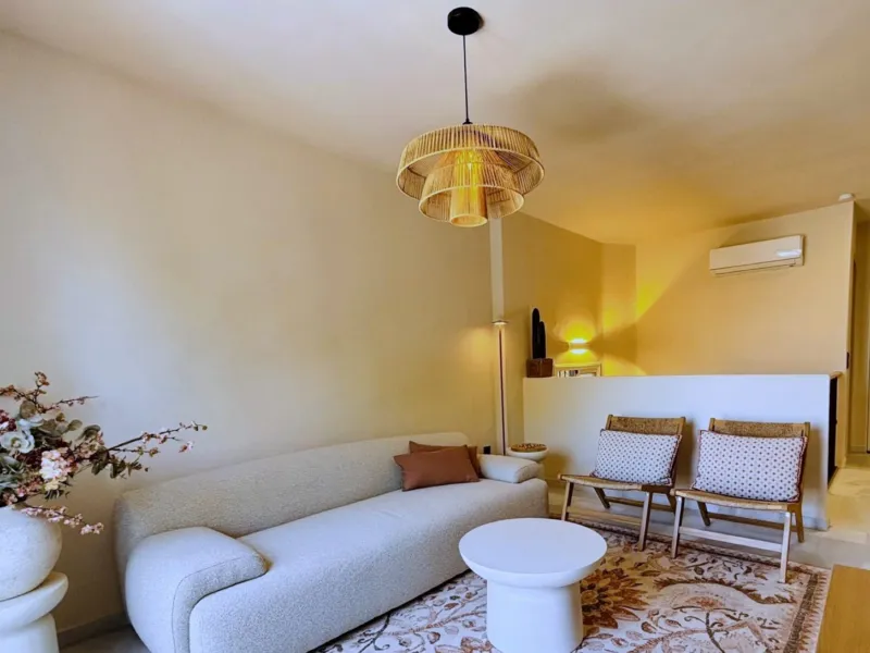 Living room with bouclé sofa, rattan pendant and woven chairs
