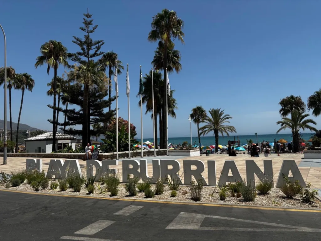 Playa de Burriana sign with palm trees and the sea