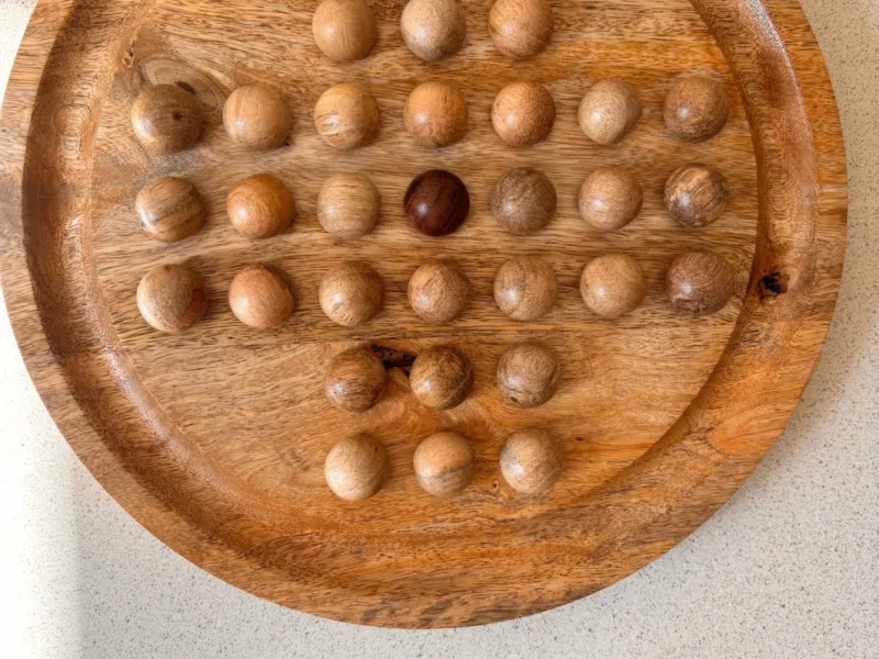 Wooden solitaire board game and TV remote